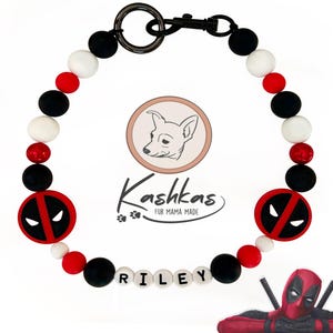 May include: A dog collar featuring a Deadpool design. The collar has black, white, and red beads, with two Deadpool logo emblems. The name "RILEY" is spelled out in white letter beads. The collar is made by Kashkas Fur Mama Made.
