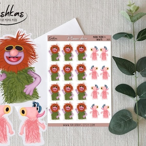 May include: A collection of stickers featuring Muppet characters. The stickers include a large, orange-haired character with sunglasses and a green outfit, along with smaller stickers of the same character and pink creatures. The stickers are from Kashkas Fur Mama Made.