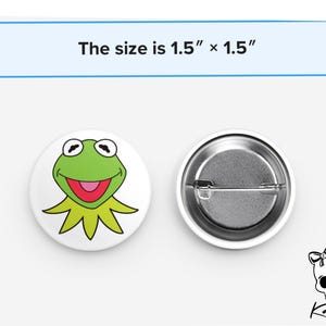May include: A 1.5 inch by 1.5 inch button featuring a cartoon image of Kermit the Frog from The Muppets. The button is white with a green frog face and a red mouth. The back of the button is silver.