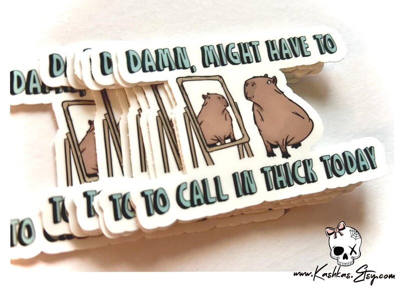May include: A stack of white stickers with the text "DAD DAMN, MIGHT HAVE TO TO TO CALL IN THICK TODAY" in blue and green letters. The stickers feature a cartoon illustration of a capybara looking at itself in a mirror.