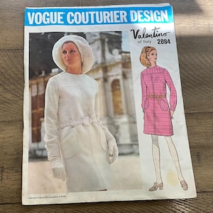 May include: A vintage Vogue Couturier Design pattern featuring two fashion illustrations. One shows a woman in a white coat and hat, the other in a pink dress. The pattern is labeled "Valentino of Italy 2084".