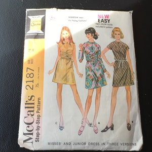 May include: McCall's sewing pattern number 2187 for a misses' and junior dress in three versions. The pattern includes a two-color guide and is labeled "New Easy". The pattern shows three different versions of the dress: one in yellow, one in a colorful print, and one in a plaid print.