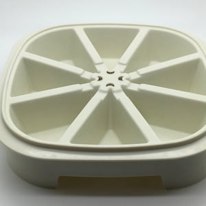 May include: White plastic tray with eight sections, each shaped like a slice of pie. The tray has a raised rim and a base with a cutout for easy handling.