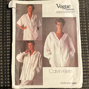 May include: Vogue Patterns sewing pattern featuring a Calvin Klein design. The pattern includes images of a white button-down shirt and a long-sleeve shirt with vertical stripes. The pattern is labeled "American Designer" and includes the pattern number 1509.