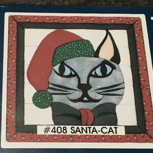 May include: A gray cat wearing a red and green Santa hat with a black bow tie. The image is framed with a red and white border and the text '#408 SANTA-CAT' is printed below the cat.