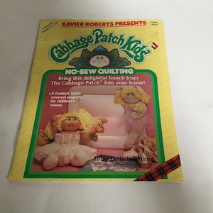 May include: A vintage Cabbage Patch Kids "No-Sew Quilting" book. The cover features a yellow and green design with the text "Xavier Roberts Presents" and "Cabbage Patch Kids." The book includes instructions for making padded fabric projects for children's rooms, including a "Bitsy Ballerina Mirror."