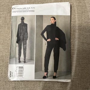 May include: A sewing pattern for a black jumpsuit with a long-sleeved top and a cape. The pattern is from the Donna Karan Collection and is for sizes 6-10-12-14-16-18. The pattern number is V1417.