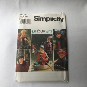 May include: Simplicity sewing pattern for children's hats and scarves. The pattern includes instructions for making a variety of styles, including a beanie, a beret, and a scarf. The pattern is illustrated with photos of children wearing the finished garments.