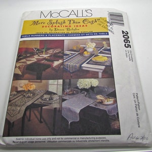 May include: McCall's sewing pattern 2065 for table runners and placemats. The pattern includes four different designs: a patchwork design, a striped design, a floral design, and a dotted design. The pattern is titled "More Splash Than Cash Decorating Ideas by Donna Babylon".