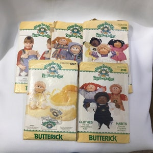 May include: Five vintage Cabbage Patch Kids sewing patterns featuring illustrations of dolls wearing different outfits. The patterns are for making clothes and habits for Cabbage Patch Kids dolls. The patterns are from the Butterick company.