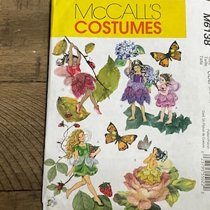 May include: A McCall's Costumes sewing pattern envelope, M6138, featuring illustrations of fairies in various outfits. The cover displays fairies with wings, butterflies, strawberries, and flowers, with the text McCall's Costumes printed in yellow and red.