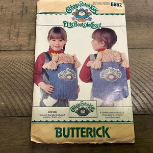 Op de afbeelding: Een Butterick naaipatroon envelop 6662 voor Cabbage Patch Kids. De voorkant toont twee kinderen in rode shirts en spijkeroveralls met een poppendrager. De tekst bevat Cabbage Patch Kids, P'tits Bouts de Choux en Butterick.
