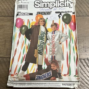May include: Simplicity sewing pattern featuring costumes for Milky Way, Snickers, and 3 Musketeers candy bars. The pattern includes images of people wearing the costumes, with balloons in the background. The pattern is size A (SM-LG).