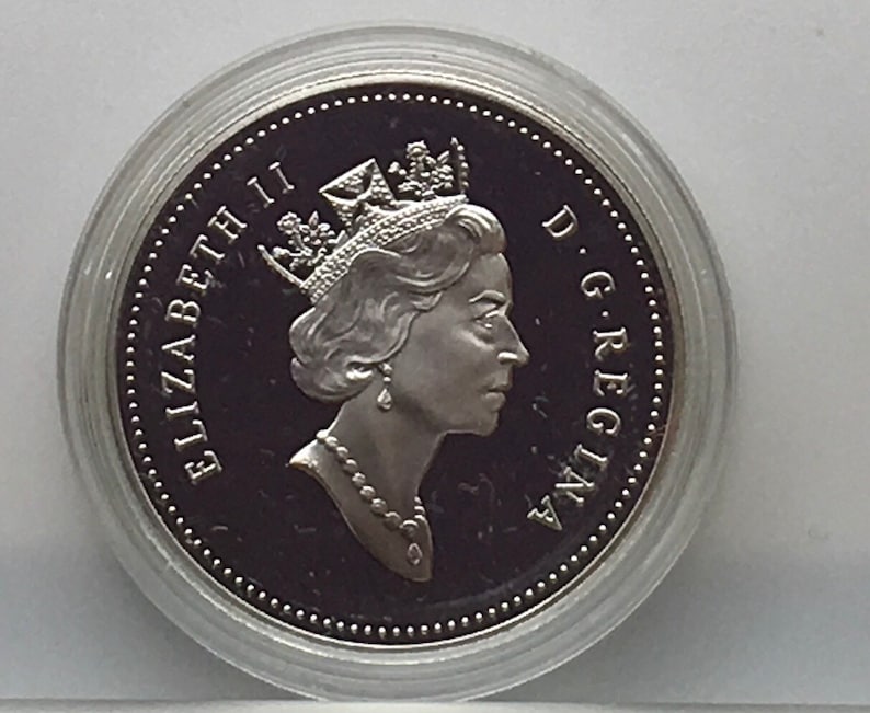 May include: Silver coin featuring a profile of Queen Elizabeth II with the inscription "ELIZABETH II D.G. REGINA" around the edge.