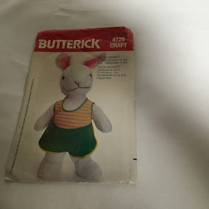 May include: A vintage sewing pattern for a white rabbit plush toy wearing a yellow and green striped outfit. The pattern is from Butterick and is labeled 4729 Craft. The text on the pattern reads "Jack Rabbit Athletic Director of the S.S. Happiness Crew" and "Jack Rabbit (Jacques le lapin) Directeur de l'athlétisme sur le S.S. Happiness."