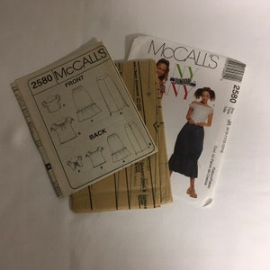 May include: A sewing pattern for a skirt and top. The pattern is from McCall's and is for juniors sizes 8-10, 11-12, and 13-14. The pattern includes instructions for making a skirt with a drawstring waist and a ruffled hem, and a top with a ruffled neckline and short sleeves.