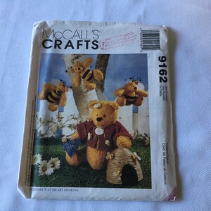 May include: A sewing pattern for making a teddy bear with a bee theme. The pattern is from McCall's Crafts and is number 9162. The pattern includes instructions for making a beehive and a teddy bear wearing a red jacket.