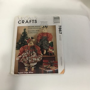 Op de afbeelding: Naai-patroon 7867 van McCall's Crafts voor het maken van twee rendierpoppen. Het patroon bevat instructies voor het maken van een mannelijke en een vrouwelijke rendierpop, elk ongeveer 79 cm hoog. De poppen zijn gekleed in feestelijke kerstkledij.
