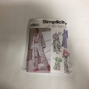 May include: A Simplicity @ Home sewing pattern for pajamas, robes, and sleepwear. The pattern envelope features a woman modeling the pajama set, robe, and pants. The pattern includes sizes PD, M/L, and XL.