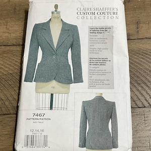 May include: A sewing pattern for a Claire Shaeffer Custom Couture Collection blazer. The pattern features a gray blazer design with a single-button closure and a tailored fit. The pattern number is 7467, with sizes 12, 14, and 16.