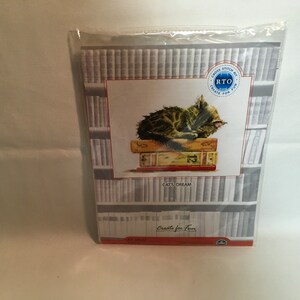 May include: Cross stitch kit featuring a cat sleeping on a stack of books. The kit is titled "Cat's Dream" and is from the brand "Create for Fun".