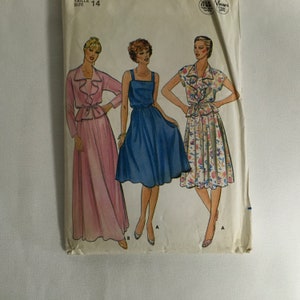 May include: Vintage sewing pattern for a dress with a ruffled collar and a skirt. The pattern includes three different styles: a pink dress with a matching jacket, a blue dress, and a floral print dress. The pattern is for size 14.