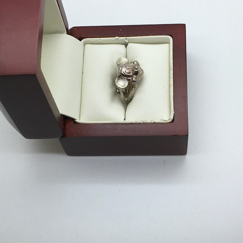 May include: A silver ring with a Mickey Mouse design in a brown ring box.