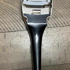May include: A metal vegetable peeler with a black handle. The top metal section features a horizontal blade and is stamped with the text 'REGAL MADE IN CANADA' and 'PATENT CANADA NO 742072'. The tool has a tapered handle and a wide, U-shaped head.