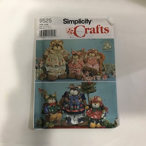 May include: Simplicity Crafts pattern 9525 for making four teddy bears. The pattern includes instructions for making a bear with a red and white gingham dress, a bear with a blue and white gingham dress, a bear with a red and white floral dress, and a bear with a blue and white reindeer print dress.