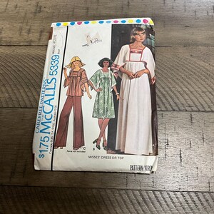 May include: A vintage McCall's pattern envelope featuring illustrations of dresses and tops. The envelope has the text "$1.75" and "5339". The illustrations depict women in various outfits, including a long white dress and a green dress.