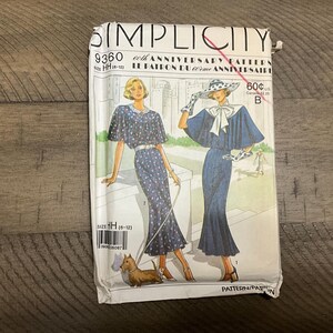 May include: Simplicity sewing pattern number 9360 for a dress. The pattern is for sizes 6-12 and is for the 60th anniversary of Simplicity patterns. The pattern shows two women wearing the dress, one in a blue floral print and the other in a solid blue. The pattern is labeled "Le Patron du 60eme Anniversaire".