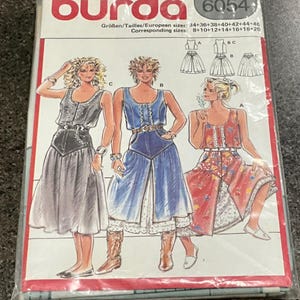 May include: A Burda 6054 sewing pattern envelope featuring illustrations of three different dress styles. The designs include a dark grey dress, a blue denim-style dress, and a red floral print dress, all with button-front bodices and full skirts.