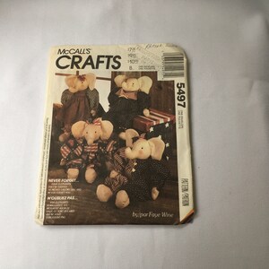 Op de afbeelding: Naai-patroon van McCall's Crafts voor vier knuffeldieren in de vorm van olifanten. Het patroon is nummer 5497 en is ontworpen door Faye Wine. De olifanten zijn gekleed in rood, wit en blauw stof met sterren en strepen.