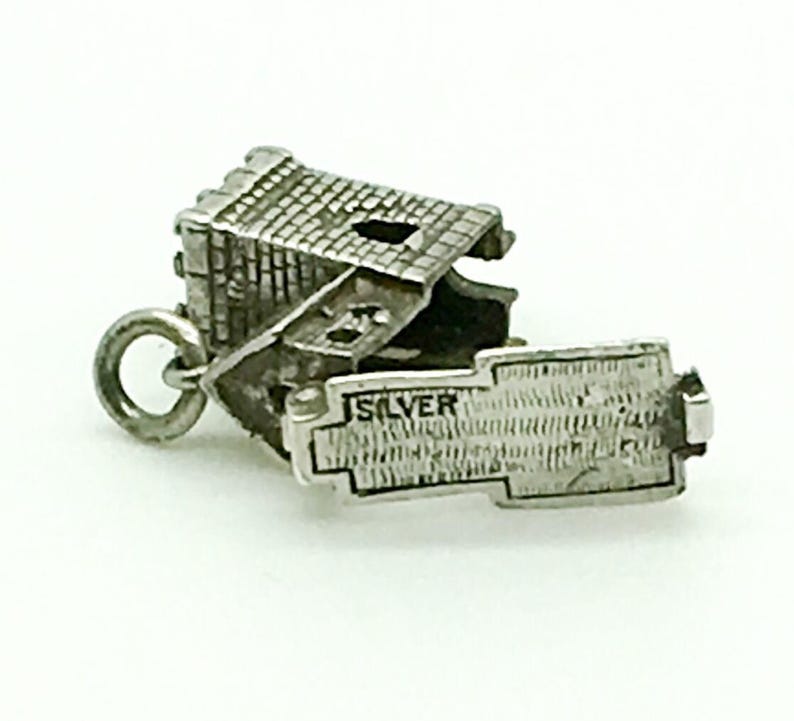 Puede incluir: Encanto de plata de una peque&ntilde;a casa con una fachada de ladrillo detallada y un techo con bisagras que se abre para revelar una inscripci&oacute;n de plata que dice "SILVER".