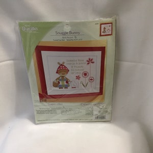Bucilla Kit de punto de cruz contado Snuggle Bunny 45011 registro de nacimiento gráfico de nacimiento anuncio conejito flores de nacimiento selladas