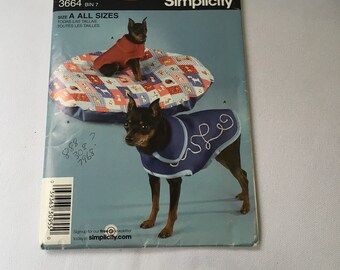 May include: Simplicity sewing pattern number 3664, bin 7, for making dog clothes. The pattern includes instructions for making a red and blue dog coat. The pattern is for all sizes. The image shows two dogs wearing the coats.