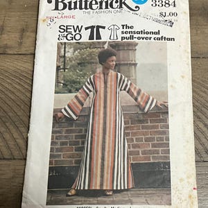 May include: A Butterick 3384 sewing pattern envelope for a pull-over caftan in size large. The cover features a photograph of a floor-length, long-sleeved caftan with vertical stripes in shades of brown, orange, white, and black.