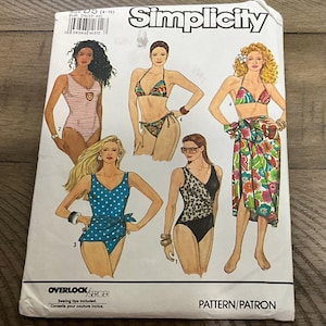 May include: A Simplicity pattern envelope featuring illustrations of various swimwear designs. The designs include a striped one-piece, a bikini, a polka dot wrap swimsuit, and a leopard print one-piece. The envelope includes the text "Simplicity" and "Pattern/Patron".