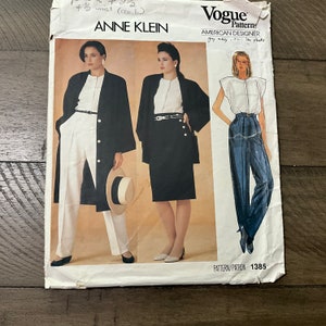 May include: A vintage Vogue sewing pattern featuring designs by Anne Klein. The pattern includes illustrations of women's fashion, including a long coat, skirt suit, and pleated trousers. The pattern number is 1385.