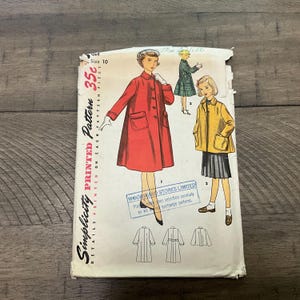 Könnte beinhalten: Vintage Simplicity Schnittmuster für einen Mädchenmantel. Das Schnittmuster ist für Größe 10 und kostet 35 Cent. Das Schnittmuster zeigt einen roten Mantel mit Taschen und einen gelben Mantel mit Taschen. Das Schnittmuster ist auf weißem Hintergrund mit schwarzem Text gedruckt.