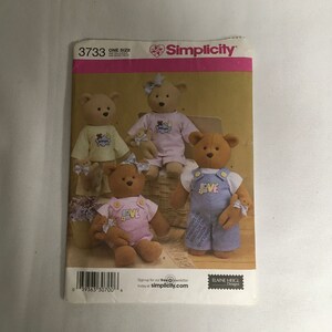 Peut inclure: Un patron de couture Simplicity pour réaliser quatre ours en peluche. Le patron comprend des instructions pour réaliser un ours portant une salopette avec le mot "LOVE" dessus, un ours portant une chemise rose avec le mot "LOVE" dessus, un ours portant une chemise rose avec un motif de lune et d'étoiles, et un ours portant une chemise bleue avec un motif de lune et d'étoiles. Le numéro du patron est 3733.