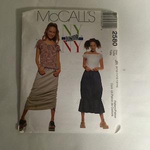 May include: McCall's pattern for a skirt, size JR (9/10-11/12-13/14). The pattern shows two different styles of skirts, one with a gathered look and the other with a more fitted look. The pattern is for a junior size and is available in a variety of sizes.