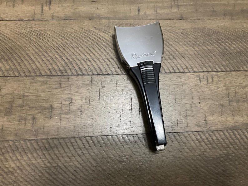 May include: A Remington brand electric shaver head attachment featuring a silver-toned metal foil top and a black plastic handle. The handle includes a textured grip section and a small silver button at the base with the word PRESS printed on it.