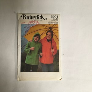 May include: A vintage sewing pattern for a hooded jacket. The pattern is for size 8 and is from Butterick, The Fashion One. The pattern number is 5004 and the price is £1.50. The pattern shows a man and woman wearing the jackets, walking under an umbrella.