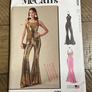 May include: McCall's M8534 sewing pattern envelope for a jumpsuit in size U5 (16-24). The front shows a gold sequined jumpsuit, a black halter jumpsuit, and a pink jumpsuit with a lace bodice. Text includes FABRICLAND NO REFUNDS NO EXCHANGES.