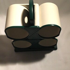 May include: A white and green mug holder with four slots. The holder is made of plastic and has a simple design.