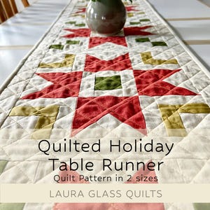 May include: Quilted holiday table runner with a star pattern in red, green, and gold on a cream background. The table runner is made of fabric and has a quilted design. The text on the image reads "Quilted Holiday Table Runner" and "LAURA GLASS QUILTS."