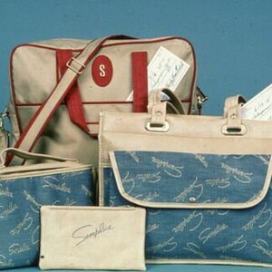 May include: A collection of vintage luggage and bags in beige and blue. The bags include a large shoulder bag, a tote bag, a small box bag, and a small pouch. The bags have red accents and the word "Simplice" is printed on the pouch.