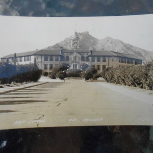 May include: Vintage black and white photograph of a large school building with a central tower and a mountain in the background. The image is slightly faded, with text at the bottom that reads "High School, Ajo, Arizona."