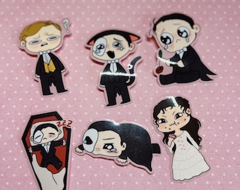 May include: Set of six colorful cartoon stickers featuring characters from the Phantom of the Opera. The stickers are printed on clear vinyl and feature a variety of expressions, including a character sleeping in a coffin, a character crying, and a character holding a rose.